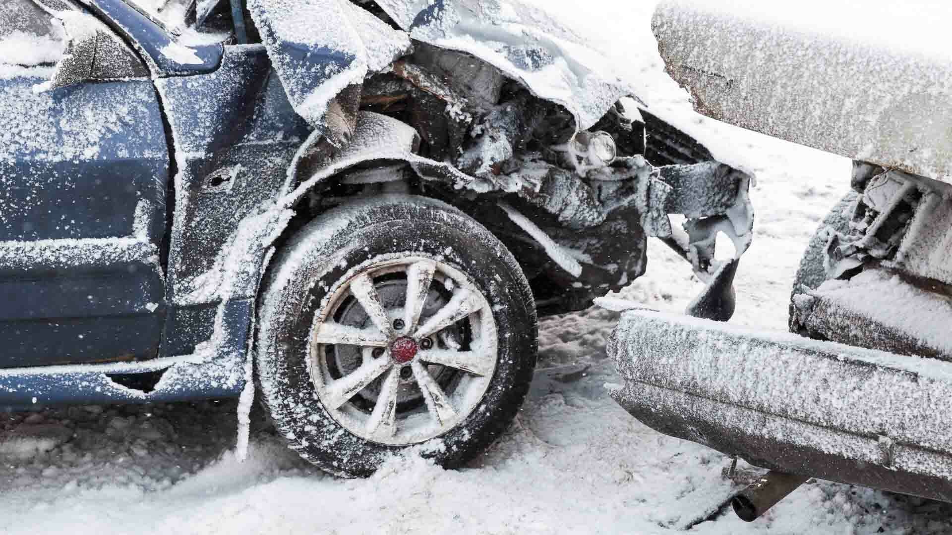 Two damaged cars with snow on their bodywork and tyres.