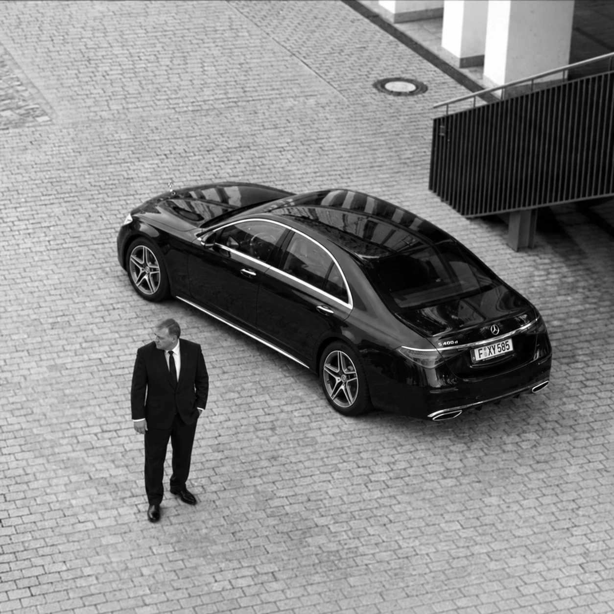 Chauffeur neben einer schwarzen Mercedes-Benz S-Klasse